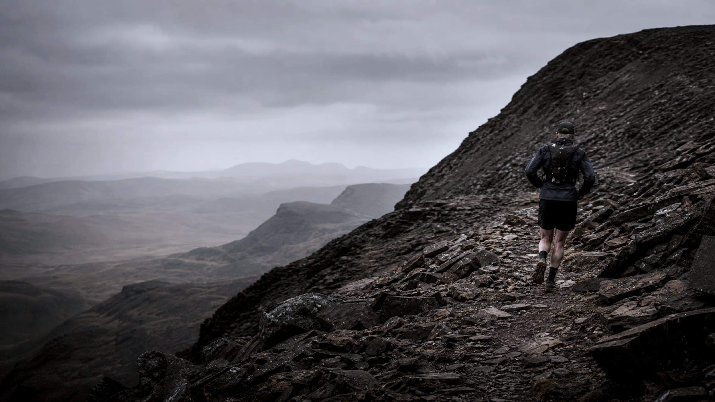 A masters-age ultra runner alone on a steep rocky desert ridge trail