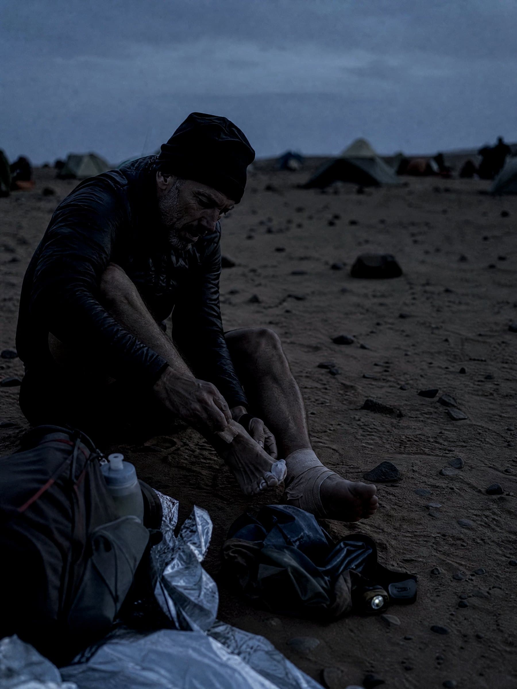 Darren Ware taping his feet at a desert bivouac before dawn